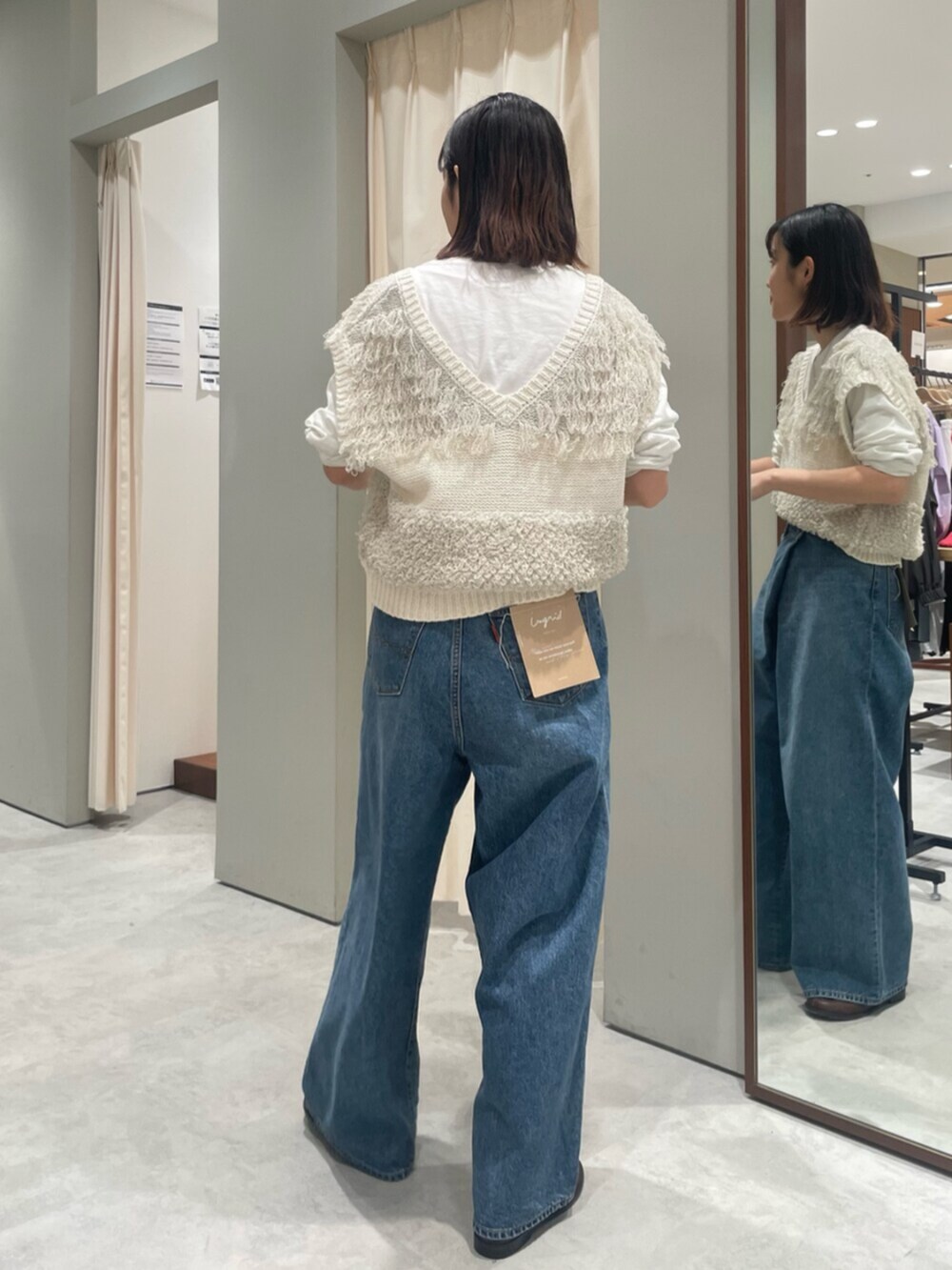 ホワイト系のベスト、ブルー系のデニムパンツ、ブラウン系のローファーを着用したレディースの春コーディネートの3枚目の写真