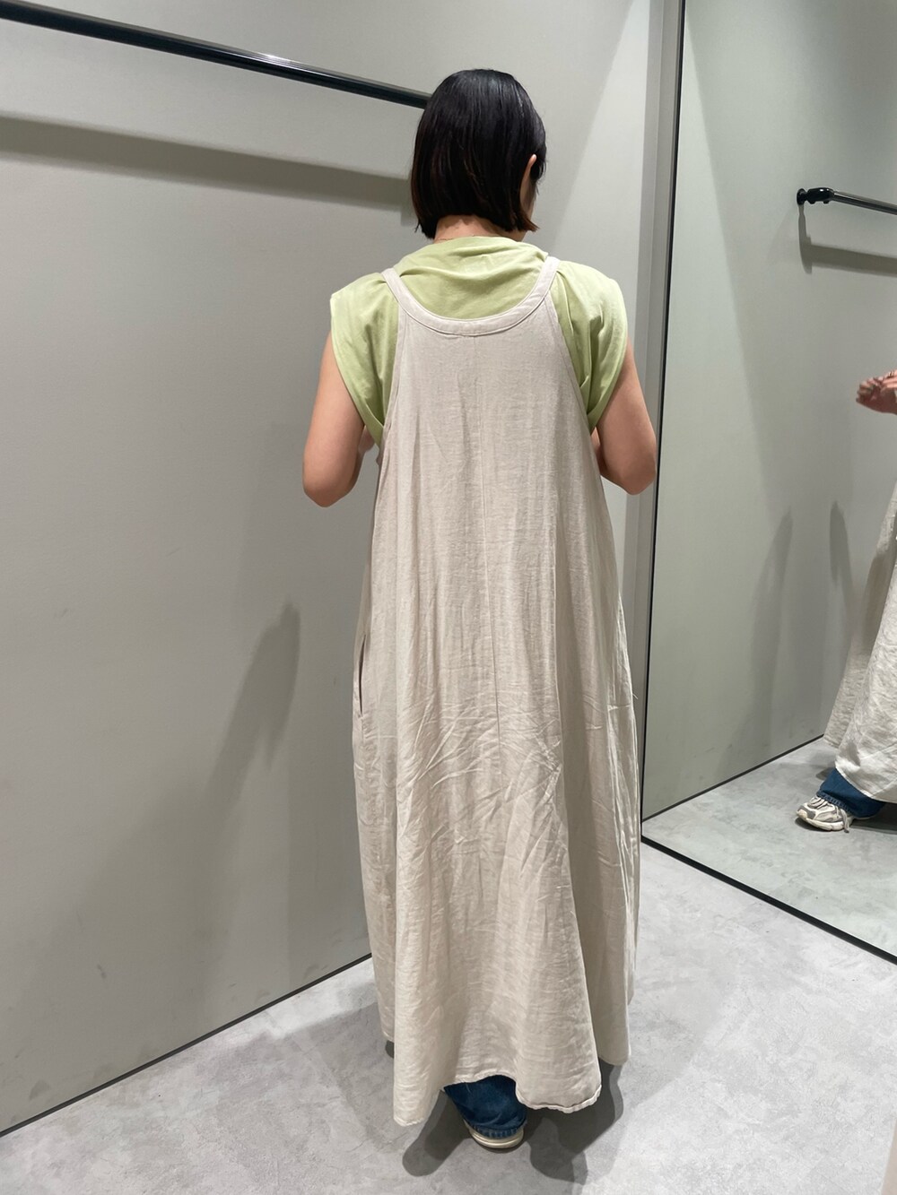 グリーン系のタンクトップ、ホワイト系のワンピース、ブルー系のデニムパンツを着用したレディースの夏コーディネートの3枚目の写真