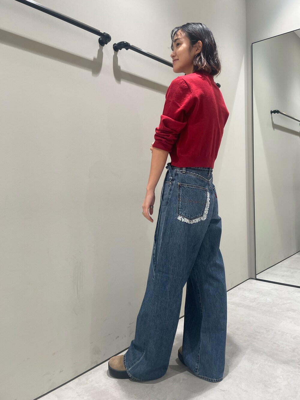 レッド系のカーディガン/ボレロ、ブルー系のデニムパンツを着用したレディースの秋コーディネートの2枚目の写真