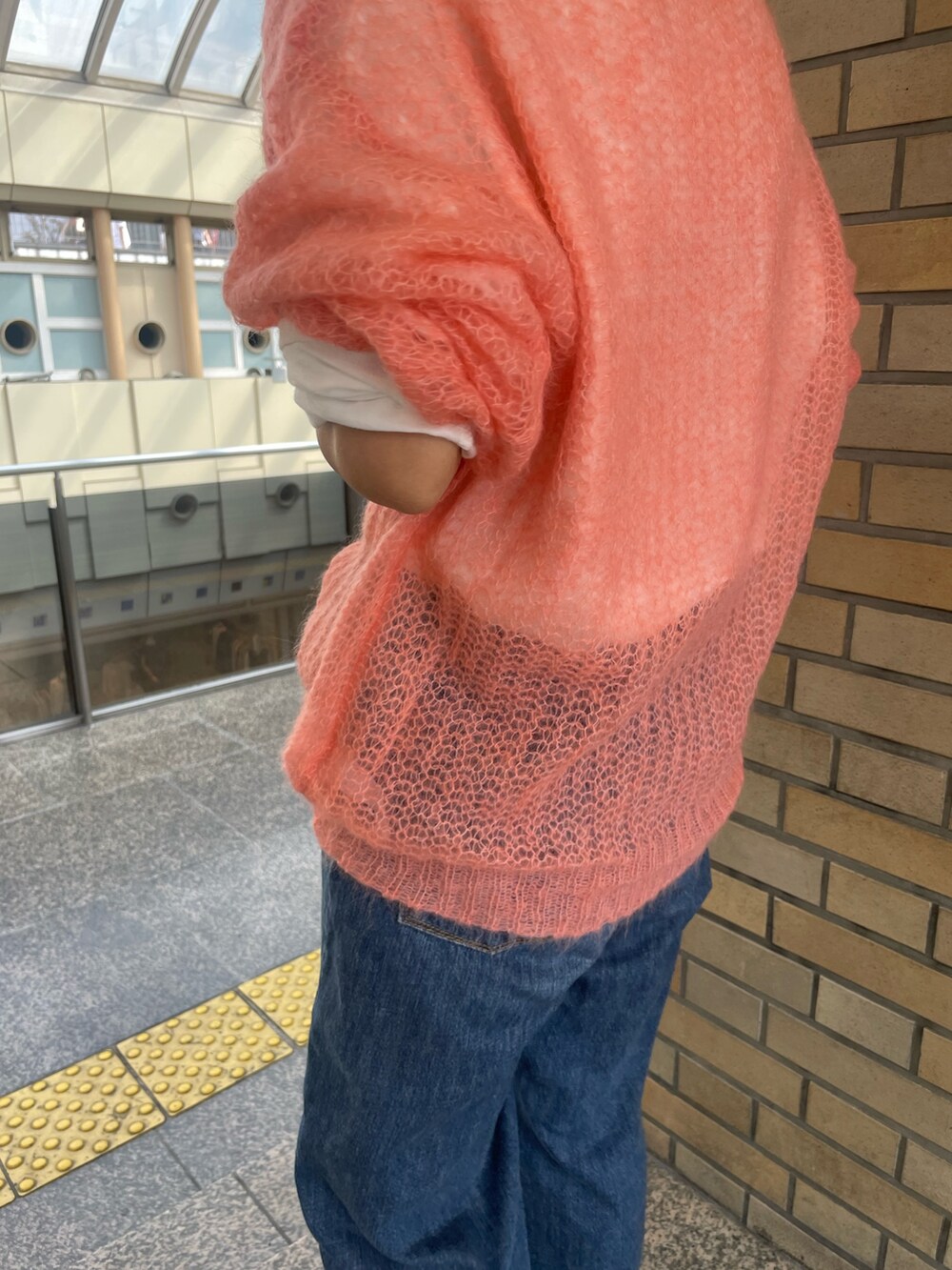 ピンク系のニット/セーター、ホワイト系のTシャツ/カットソー、ブルー系のデニムパンツを着用したレディースの秋コーディネートの4枚目の写真