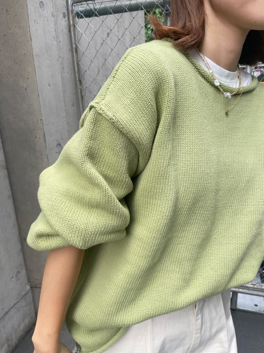 グリーン系のニット/セーター、ホワイト系のTシャツ/カットソー、ホワイト系のデニムパンツを着用したレディースの秋コーディネートの4枚目の写真