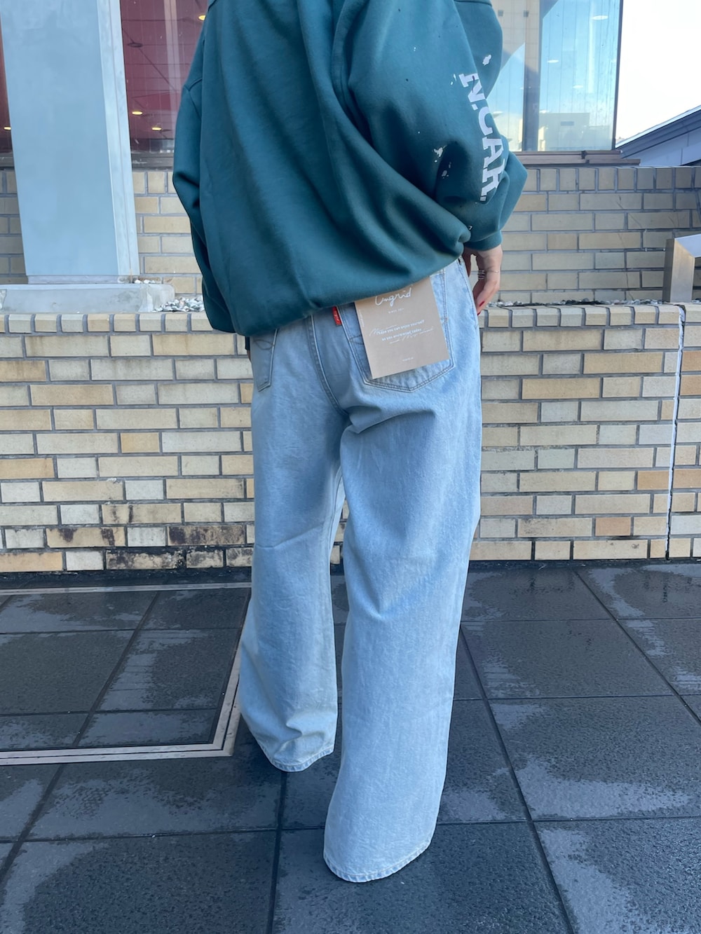 グリーン系のスウェット、ブルー系のデニムパンツを着用したレディースの冬コーディネートの6枚目の写真