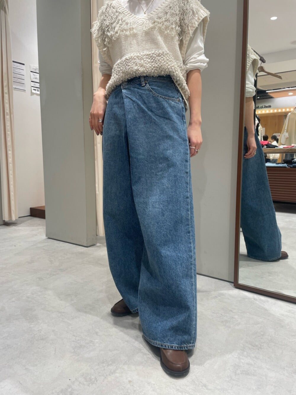 ホワイト系のベスト、ブルー系のデニムパンツ、ブラウン系のローファーを着用したレディースの春コーディネートの6枚目の写真