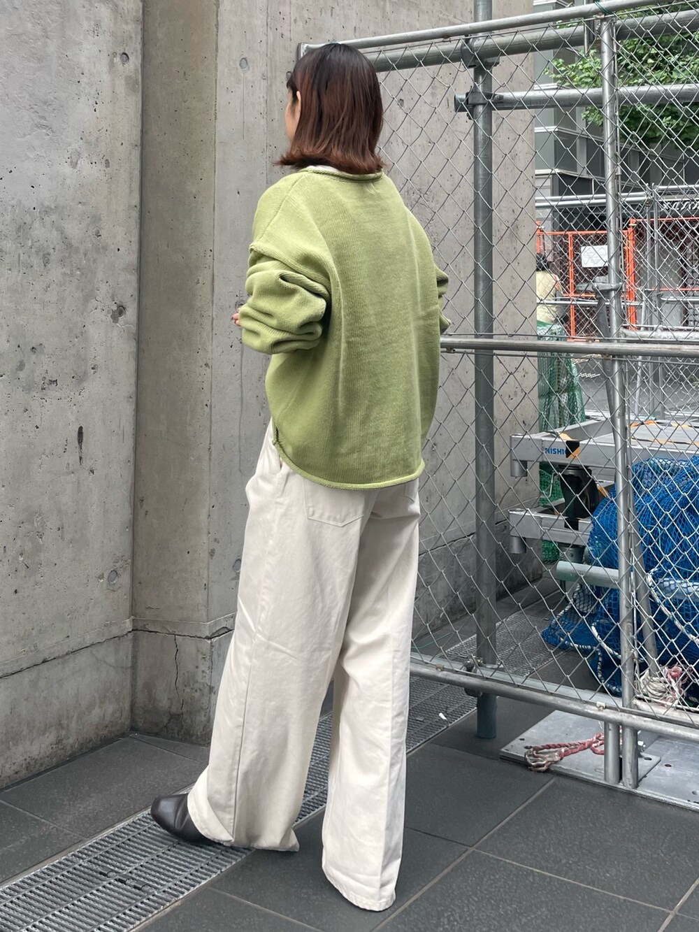 グリーン系のニット/セーター、ホワイト系のTシャツ/カットソー、ホワイト系のデニムパンツを着用したレディースの秋コーディネートの3枚目の写真