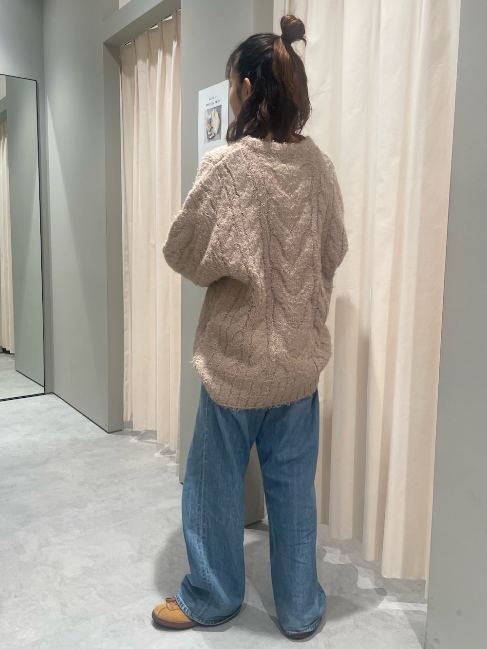 ベージュ系のニット/セーター、ブルー系のデニムパンツを着用したレディースの秋コーディネートの2枚目の写真