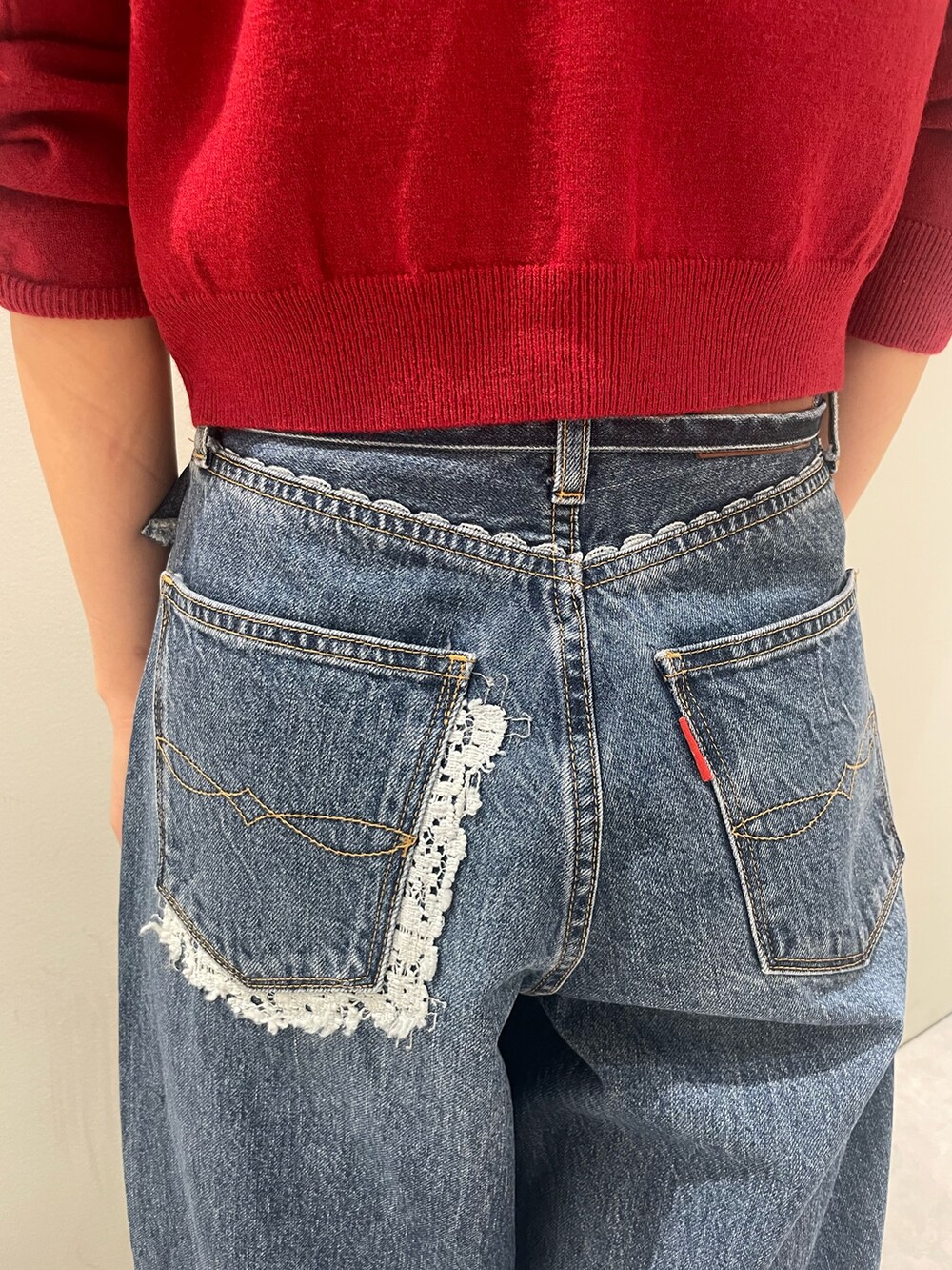 レッド系のカーディガン/ボレロ、ブルー系のデニムパンツを着用したレディースの秋コーディネートの5枚目の写真