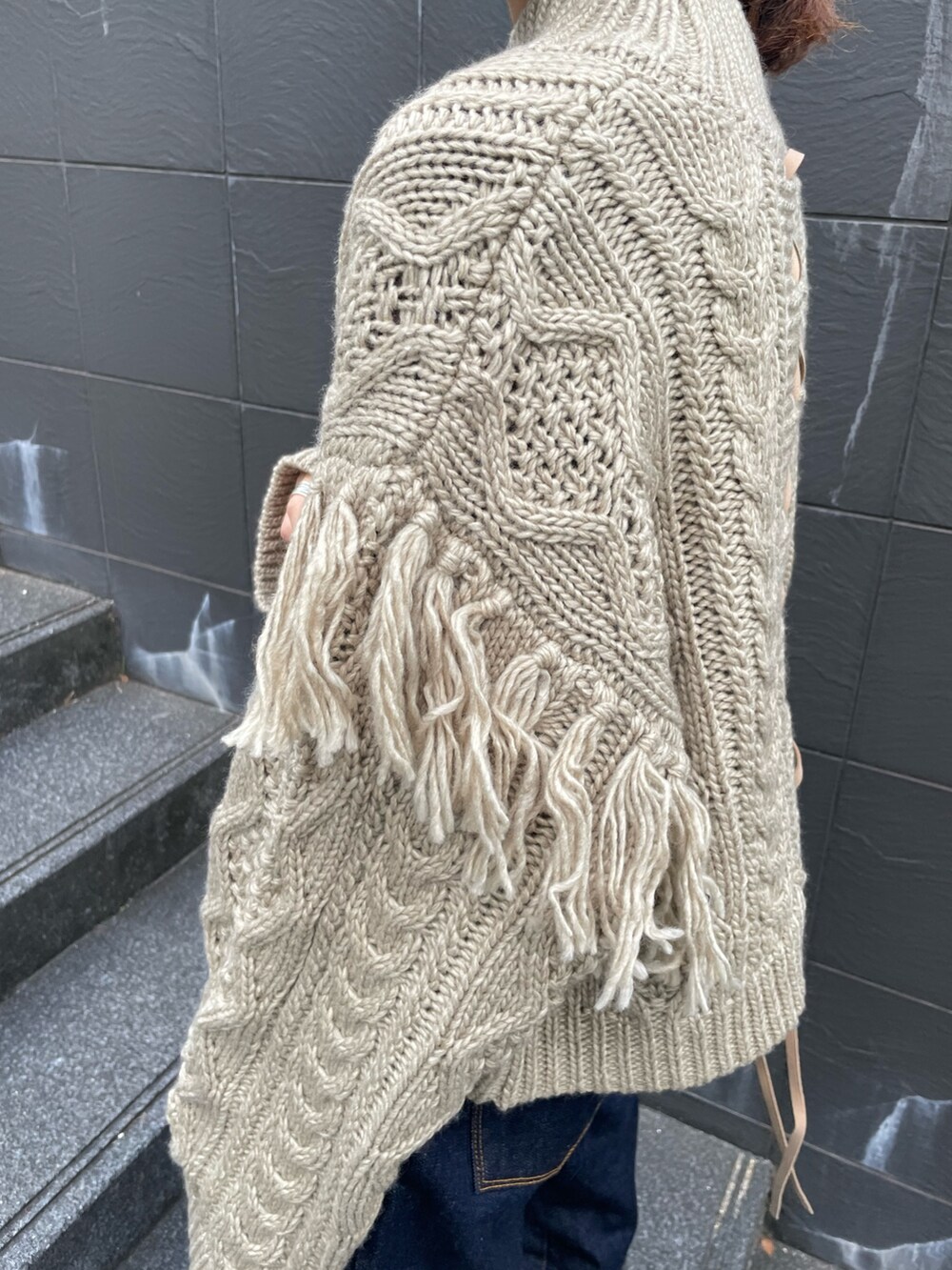 ベージュ系のニット/セーター、ブルー系のデニムパンツを着用したレディースの冬コーディネートの4枚目の写真