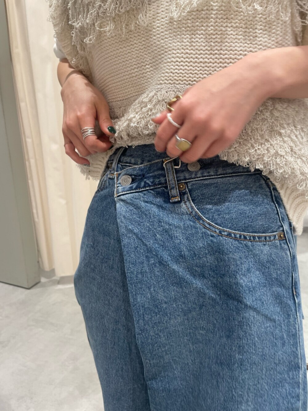 ホワイト系のベスト、ブルー系のデニムパンツ、ブラウン系のローファーを着用したレディースの春コーディネートの7枚目の写真