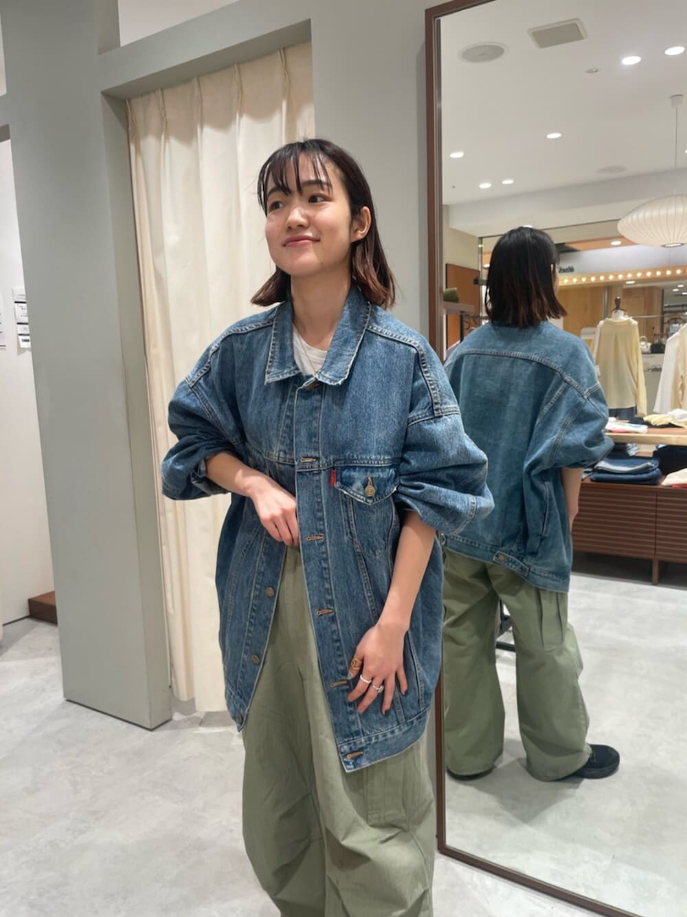 ブルー系のデニムジャケット、グリーン系のその他パンツ、ブラック系のスニーカーを着用したレディースの春コーディネートの4枚目の写真