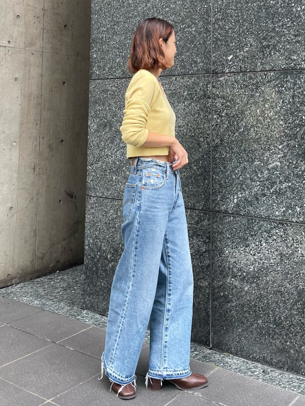 グリーン系のTシャツ/カットソー、ブルー系のデニムパンツ、ブラウン系のブーツを着用したレディースの秋コーディネートの2枚目の写真