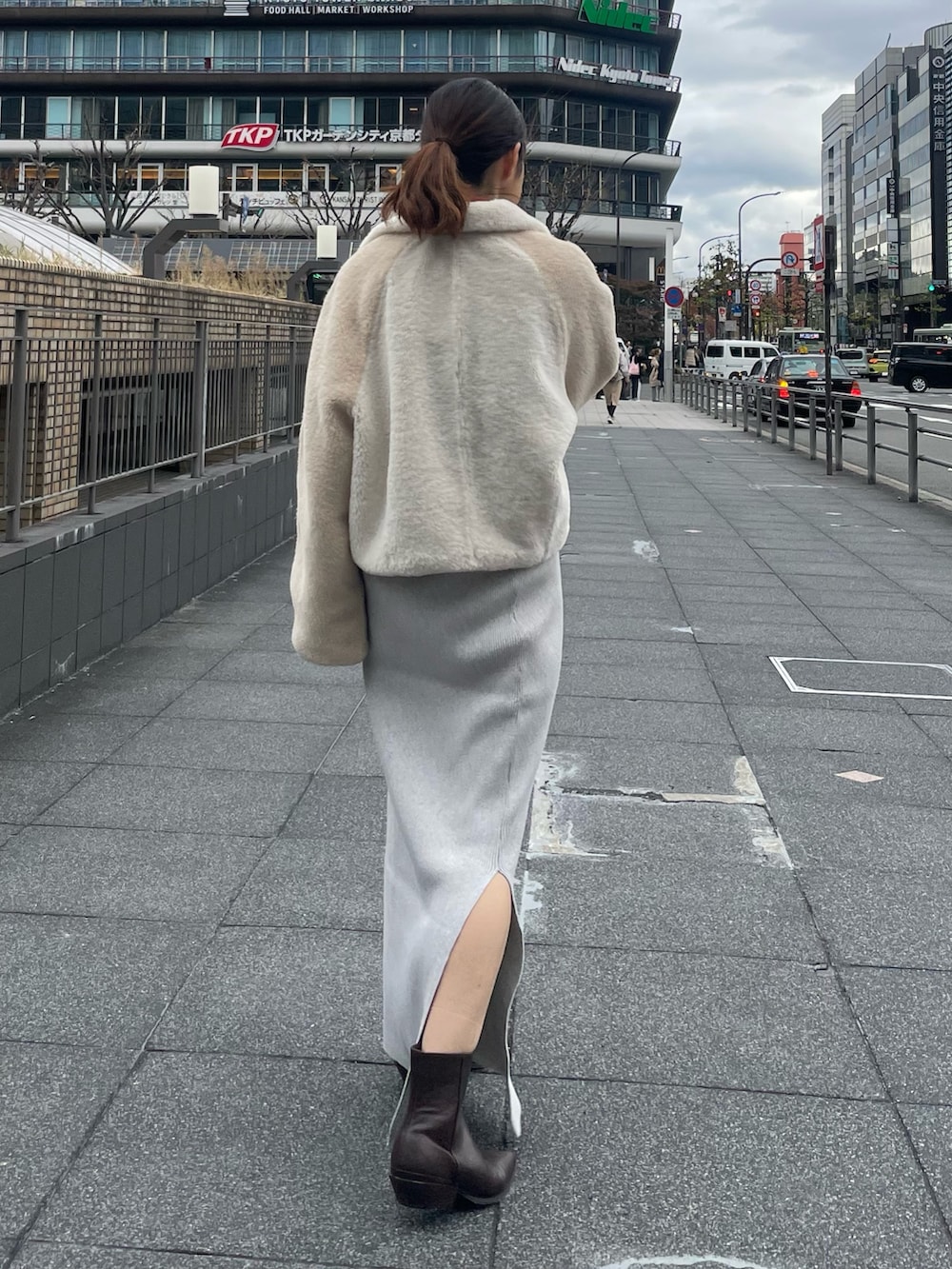 ホワイト系のブルゾン、オレンジ系のニット/セーター、グレー系のスカートを着用したレディースの冬コーディネートの3枚目の写真