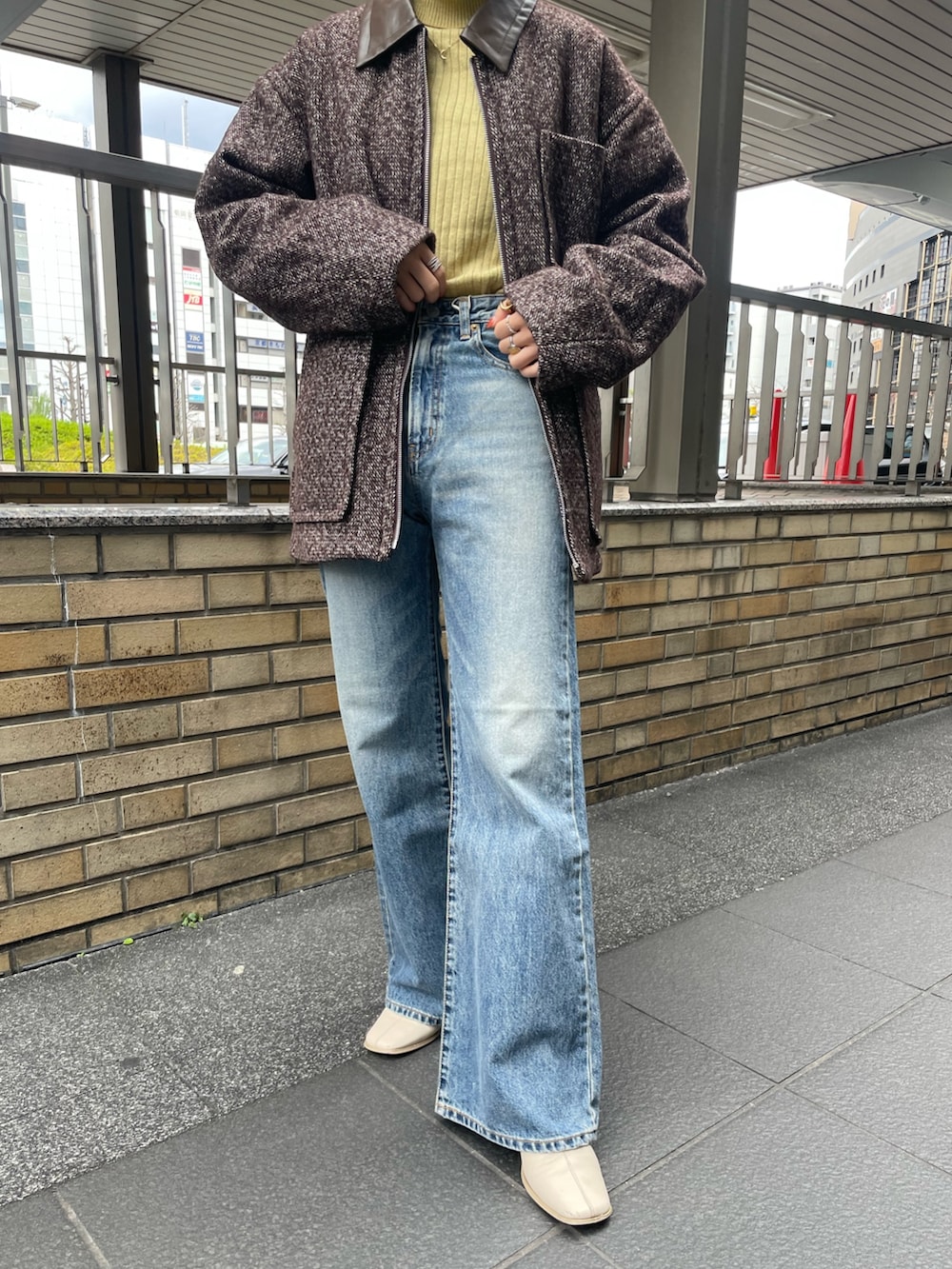 イエロー系のニット/セーター、ブラウン系のブルゾン、ブルー系のデニムパンツを着用したレディースの冬コーディネートの5枚目の写真