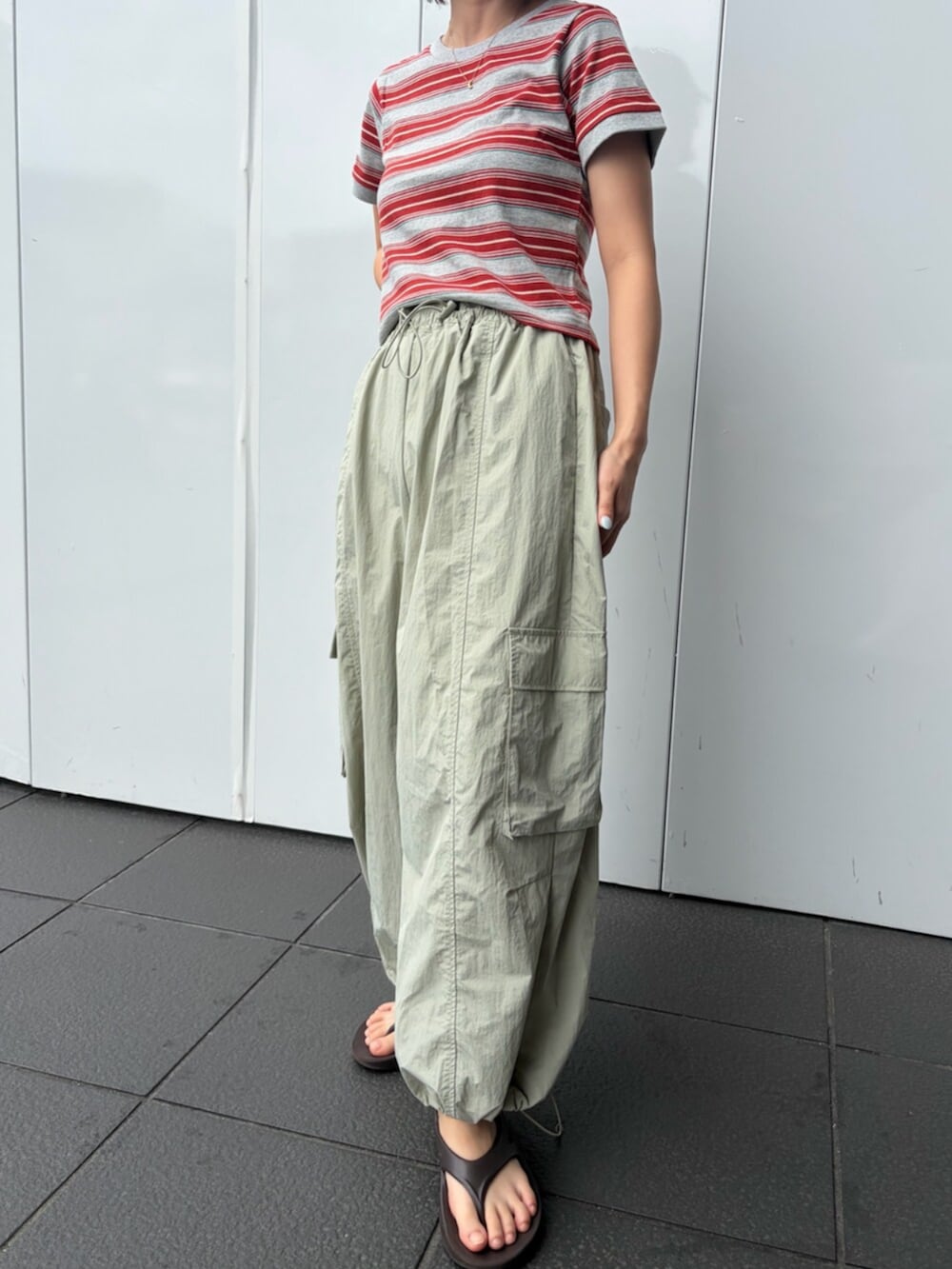 レッド系のTシャツ/カットソー、グリーン系のその他パンツ、ブラウン系のキャップを着用したレディースの夏コーディネートの4枚目の写真