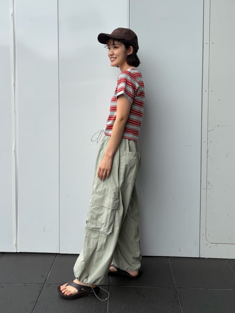 レッド系のTシャツ/カットソー、グリーン系のその他パンツ、ブラウン系のキャップを着用したレディースの夏コーディネートの2枚目の写真