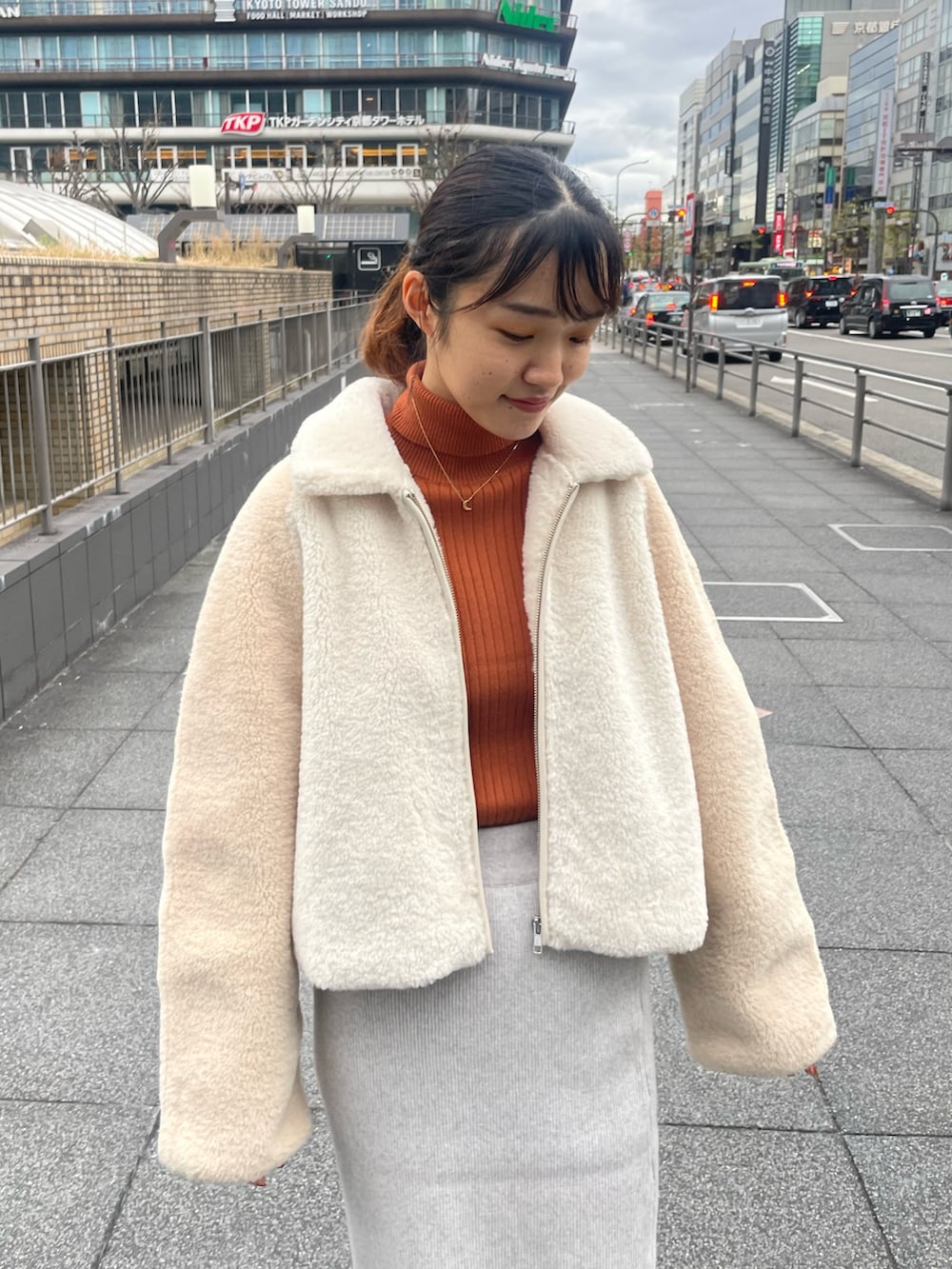 ホワイト系のブルゾン、オレンジ系のニット/セーター、グレー系のスカートを着用したレディースの冬コーディネートの4枚目の写真