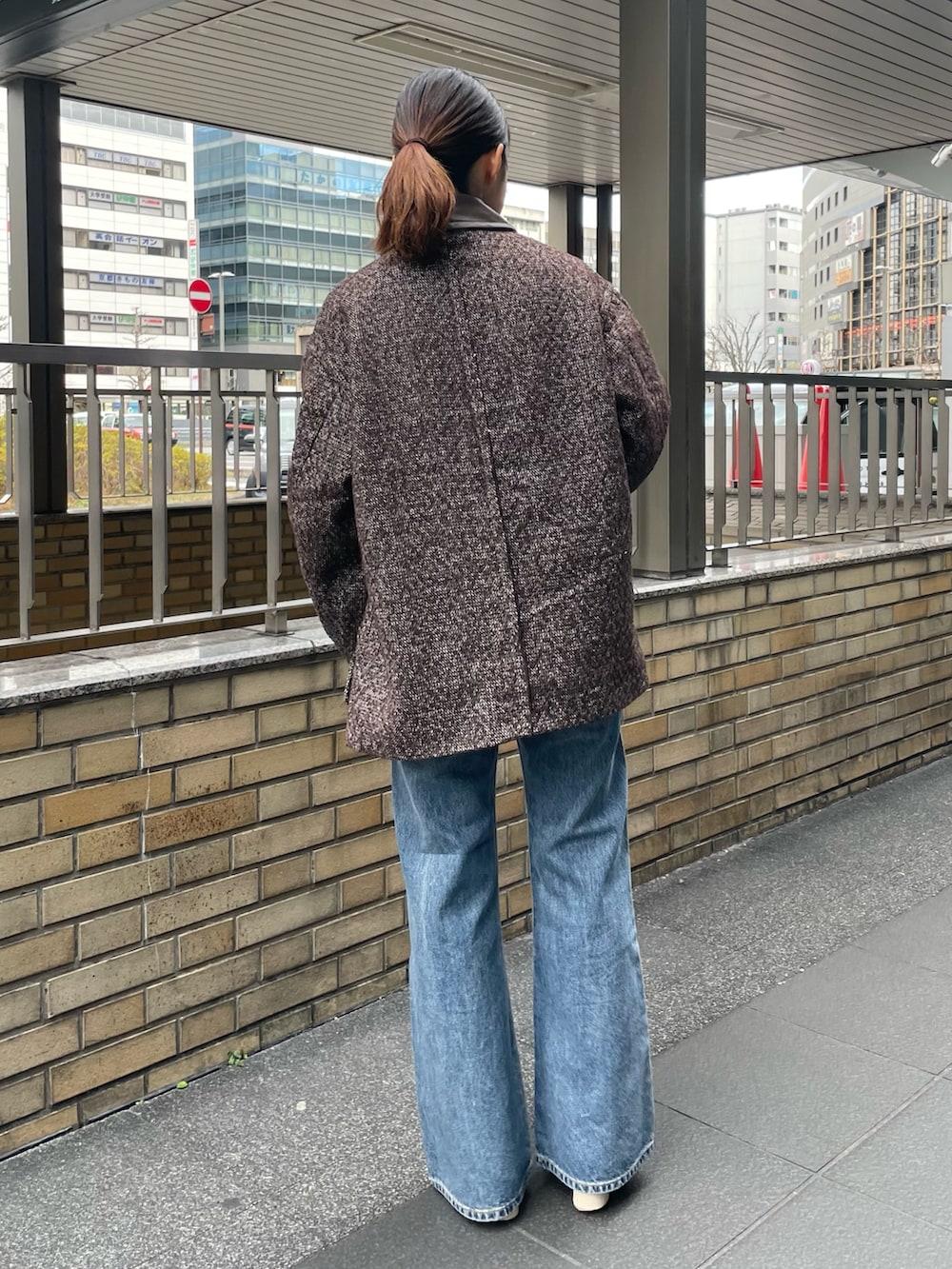 イエロー系のニット/セーター、ブラウン系のブルゾン、ブルー系のデニムパンツを着用したレディースの冬コーディネートの3枚目の写真