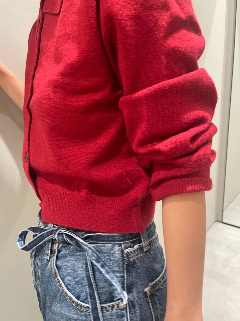 レッド系のカーディガン/ボレロ、ブルー系のデニムパンツを着用したレディースの秋コーディネートの4枚目の写真