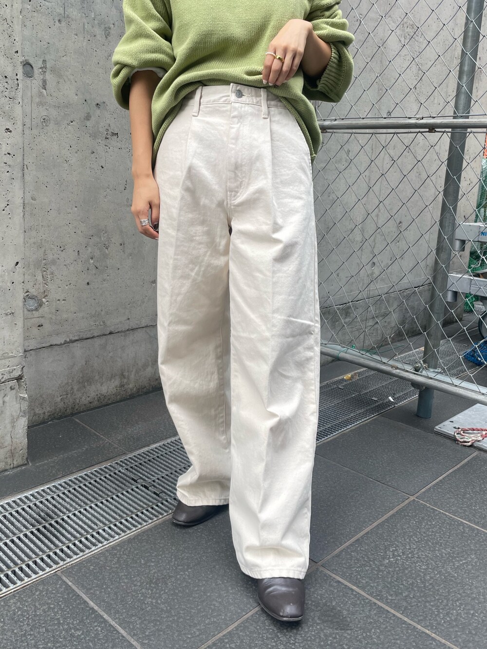 グリーン系のニット/セーター、ホワイト系のTシャツ/カットソー、ホワイト系のデニムパンツを着用したレディースの秋コーディネートの6枚目の写真