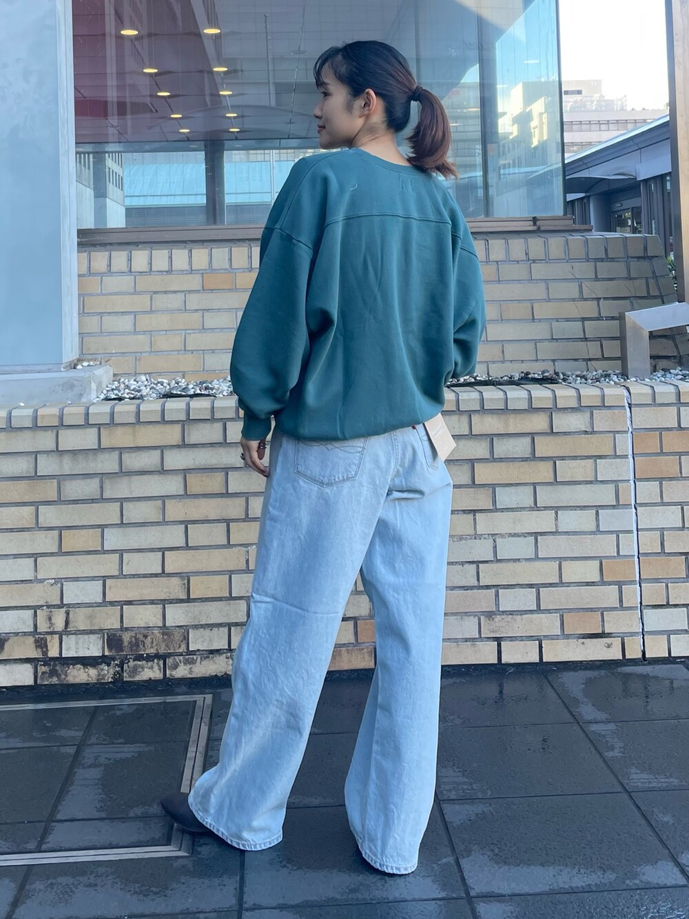 グリーン系のスウェット、ブルー系のデニムパンツを着用したレディースの冬コーディネートの3枚目の写真