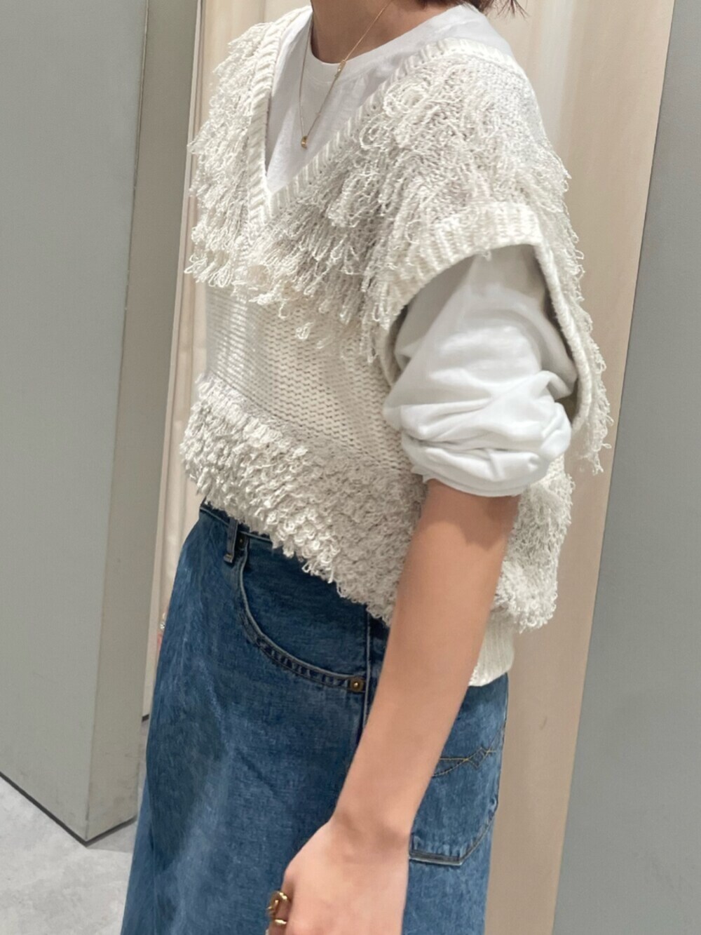 ホワイト系のベスト、ブルー系のデニムパンツ、ブラウン系のローファーを着用したレディースの春コーディネートの4枚目の写真