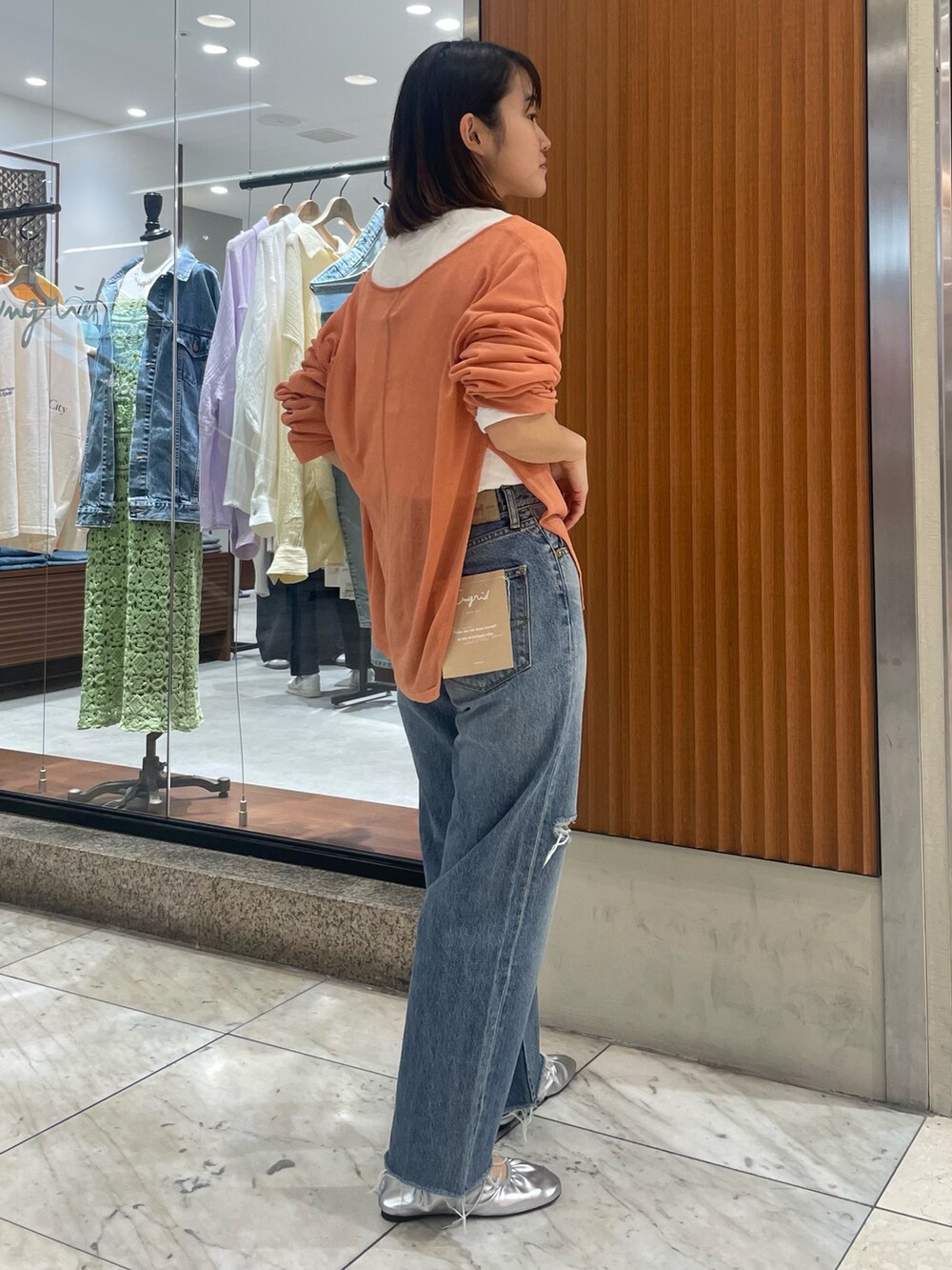 オレンジ系のニット/セーター、ブルー系のデニムパンツ、シルバー系のバレエシューズを着用したレディースの春コーディネートの3枚目の写真