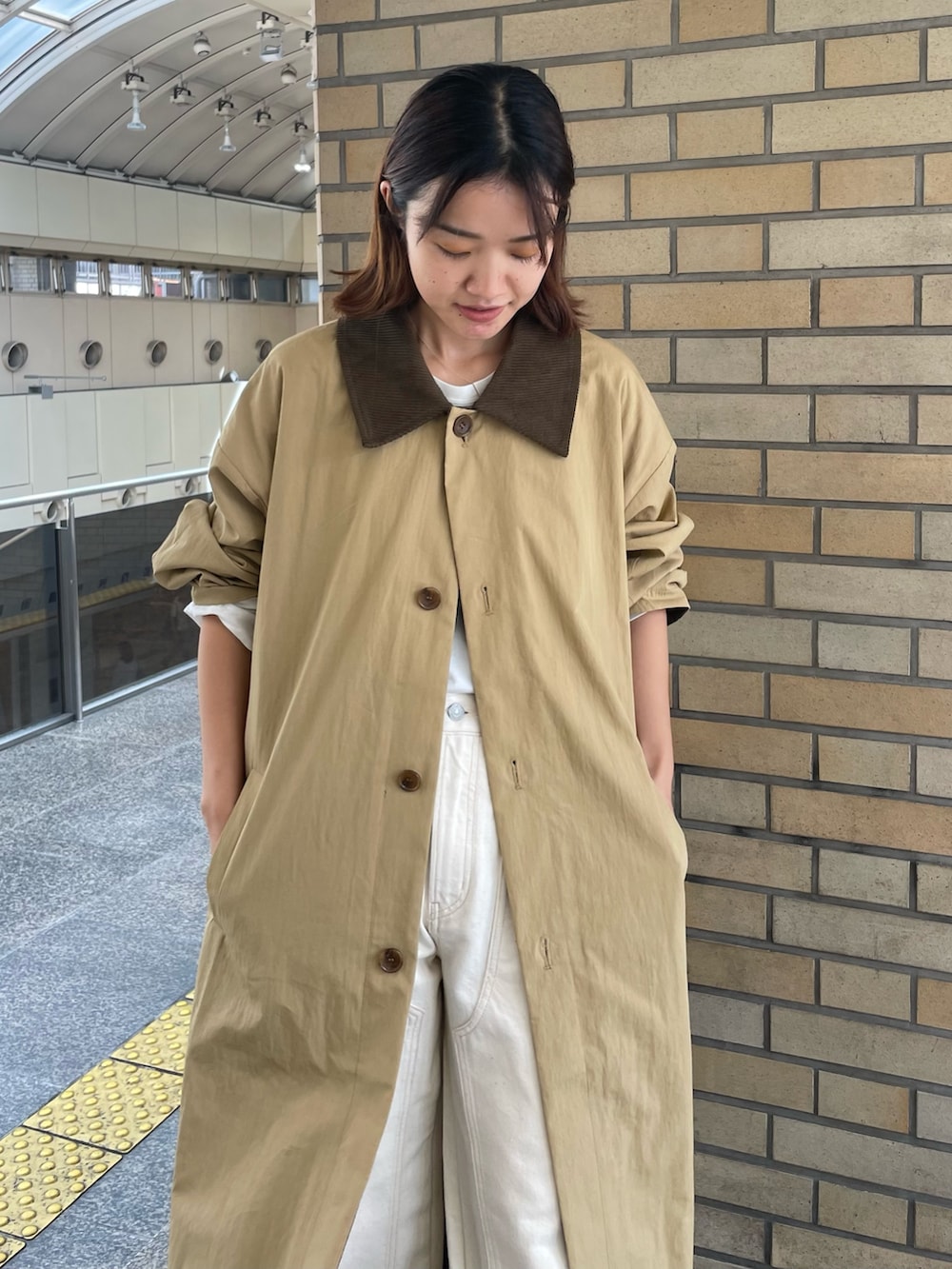 ベージュ系のステンカラーコート、ホワイト系のTシャツ/カットソー、ホワイト系のデニムパンツを着用したレディースの秋コーディネートの4枚目の写真