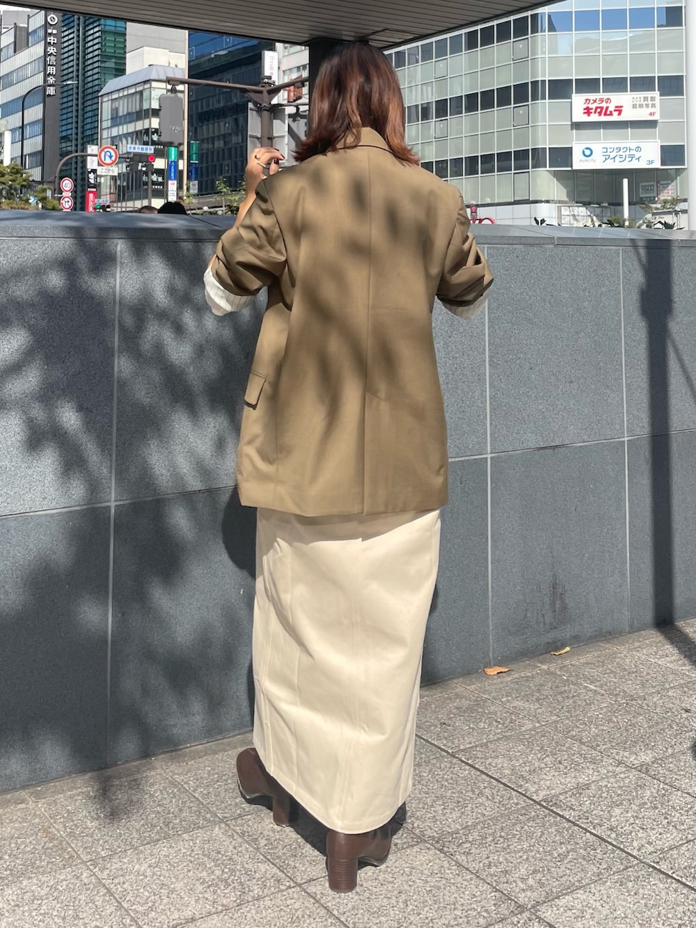 ベージュ系のテーラードジャケット、ホワイト系のTシャツ/カットソー、ベージュ系のスカートを着用したレディースの秋コーディネートの3枚目の写真