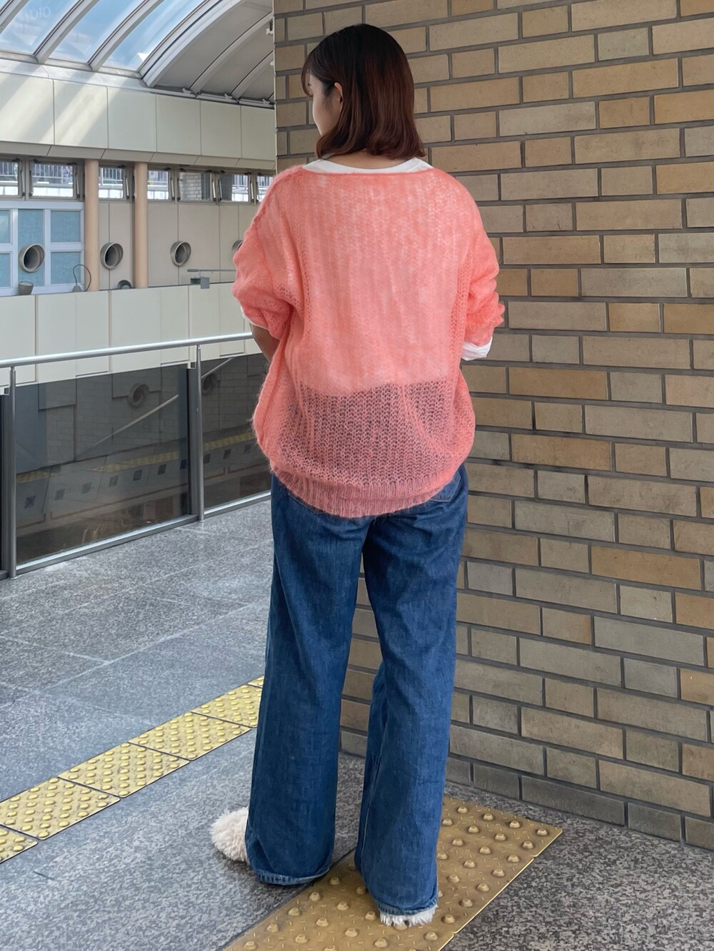 ピンク系のニット/セーター、ホワイト系のTシャツ/カットソー、ブルー系のデニムパンツを着用したレディースの秋コーディネートの3枚目の写真