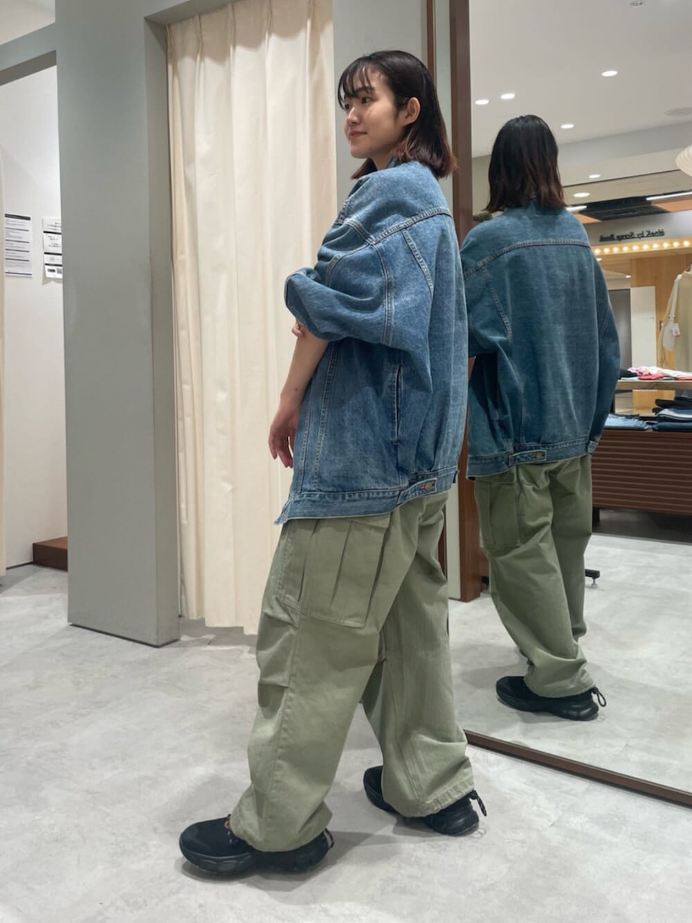 ブルー系のデニムジャケット、グリーン系のその他パンツ、ブラック系のスニーカーを着用したレディースの春コーディネートの2枚目の写真