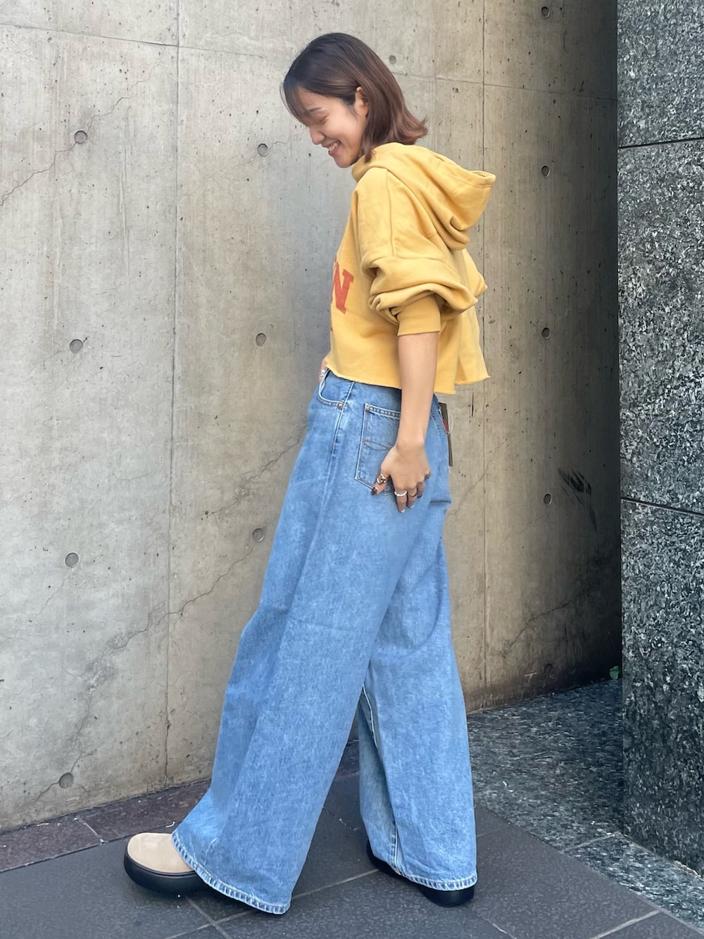 ブルー系のデニムパンツ、イエロー系のパーカーを着用したレディースの秋コーディネートの2枚目の写真