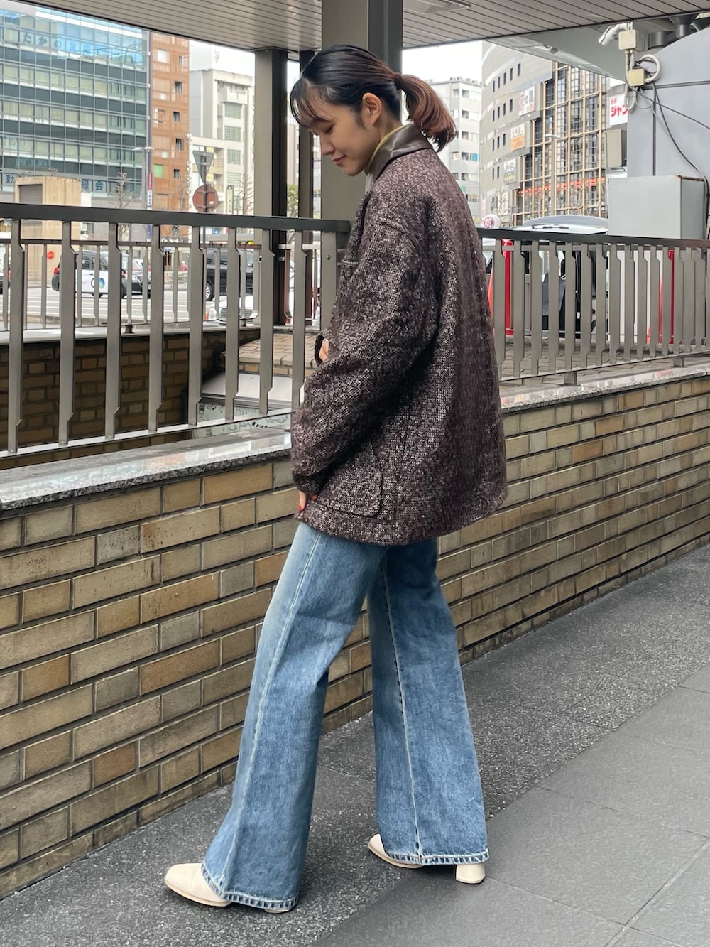 イエロー系のニット/セーター、ブラウン系のブルゾン、ブルー系のデニムパンツを着用したレディースの冬コーディネートの2枚目の写真