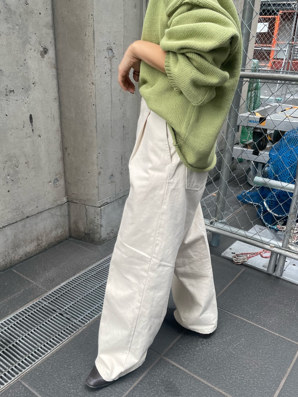 グリーン系のニット/セーター、ホワイト系のTシャツ/カットソー、ホワイト系のデニムパンツを着用したレディースの秋コーディネートの5枚目の写真