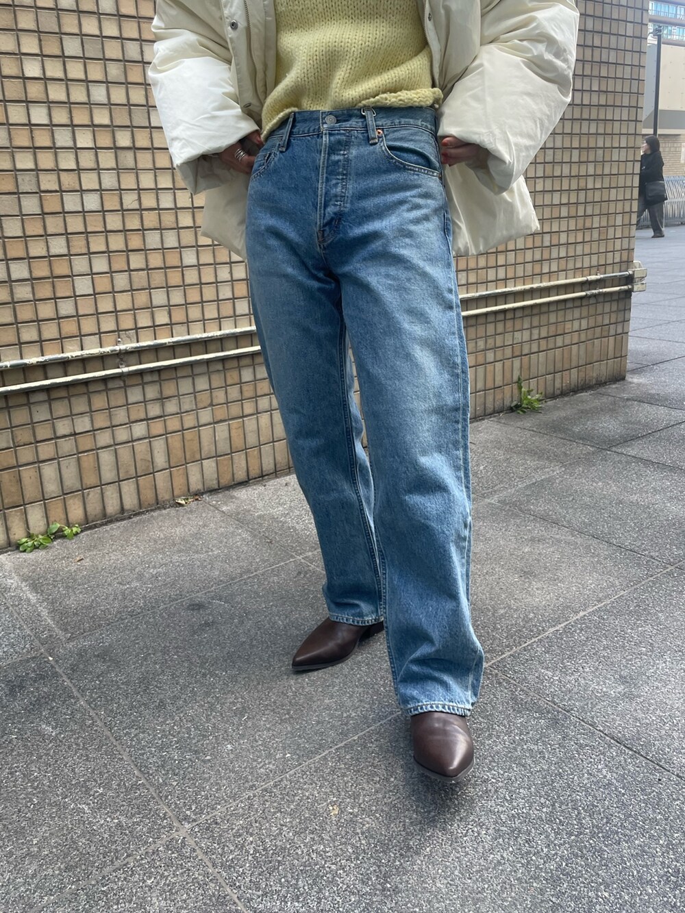 ホワイト系のダウンジャケット/コート、イエロー系のニット/セーター、ブルー系のデニムパンツを着用したレディースの秋コーディネートの5枚目の写真