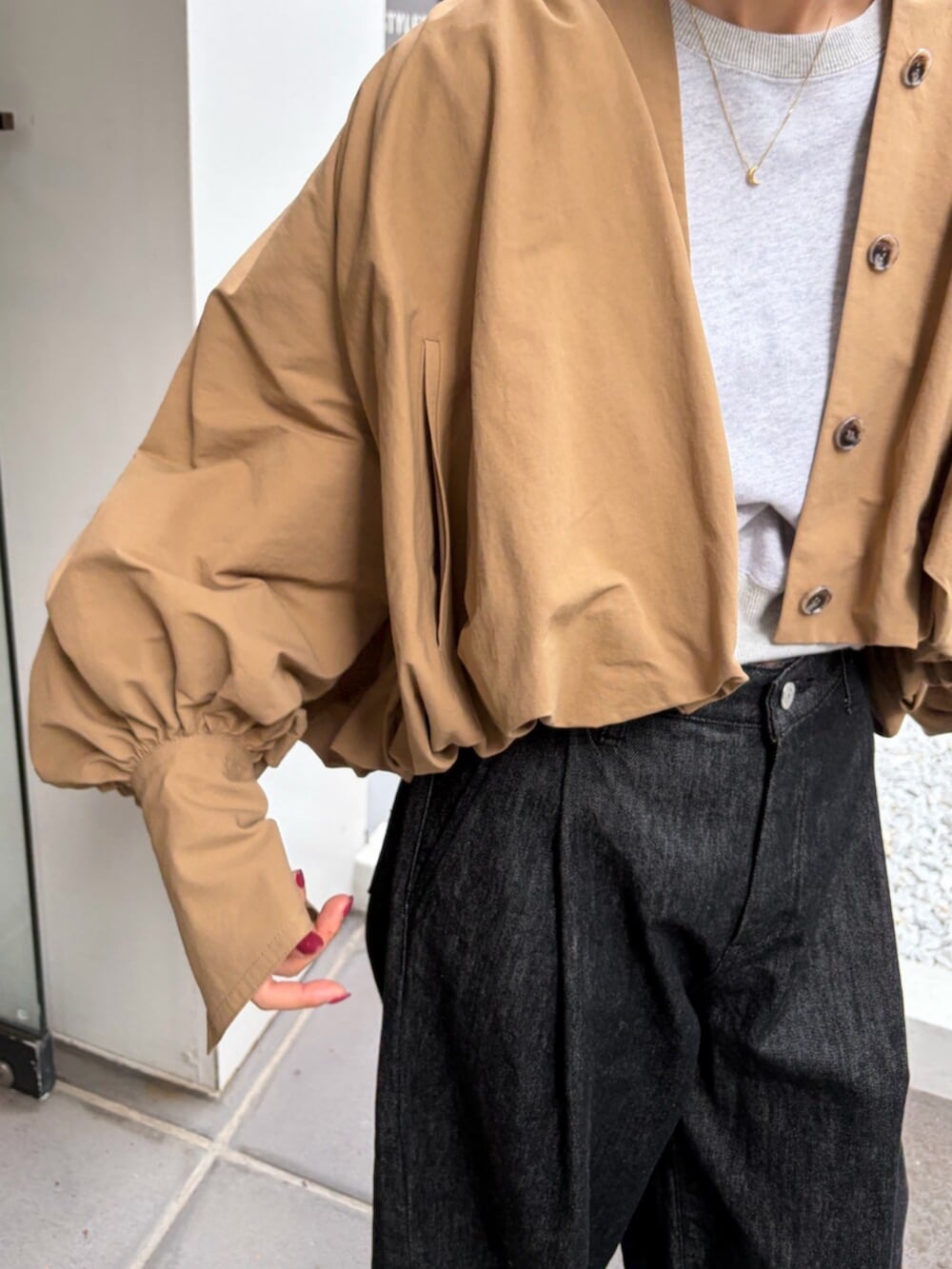 ベージュ系のブルゾン、グレー系のスウェット、ブラック系のデニムパンツを着用したレディースの秋コーディネートの4枚目の写真