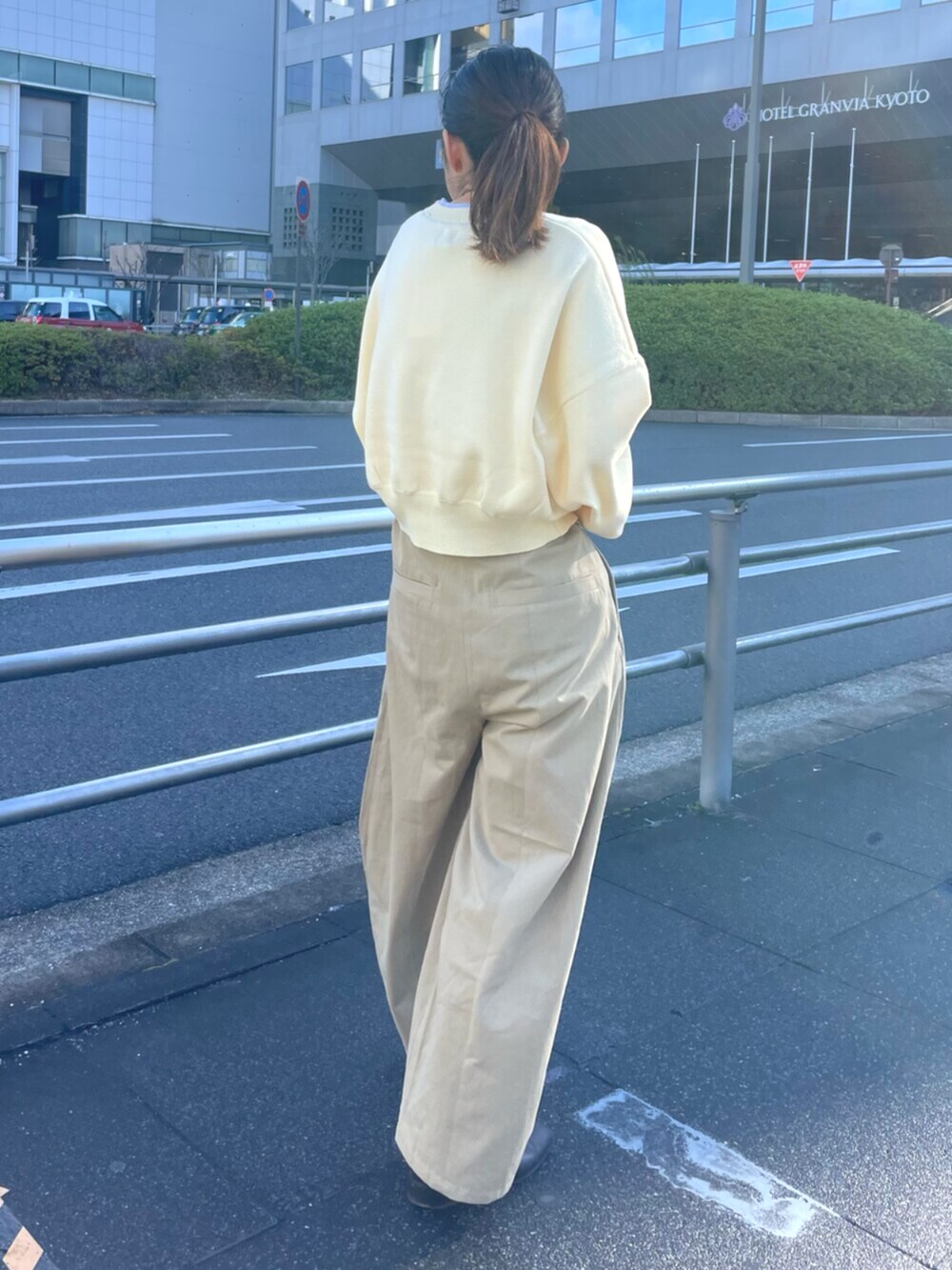 イエロー系のニット/セーター、ベージュ系のチノパンツ、ホワイト系のボストンバッグを着用したレディースの冬コーディネートの3枚目の写真