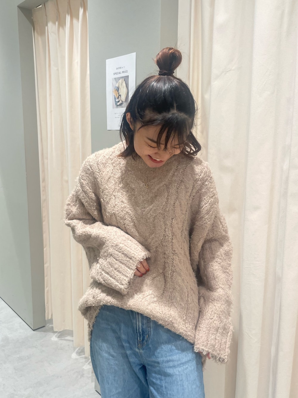 ベージュ系のニット/セーター、ブルー系のデニムパンツを着用したレディースの秋コーディネートの4枚目の写真