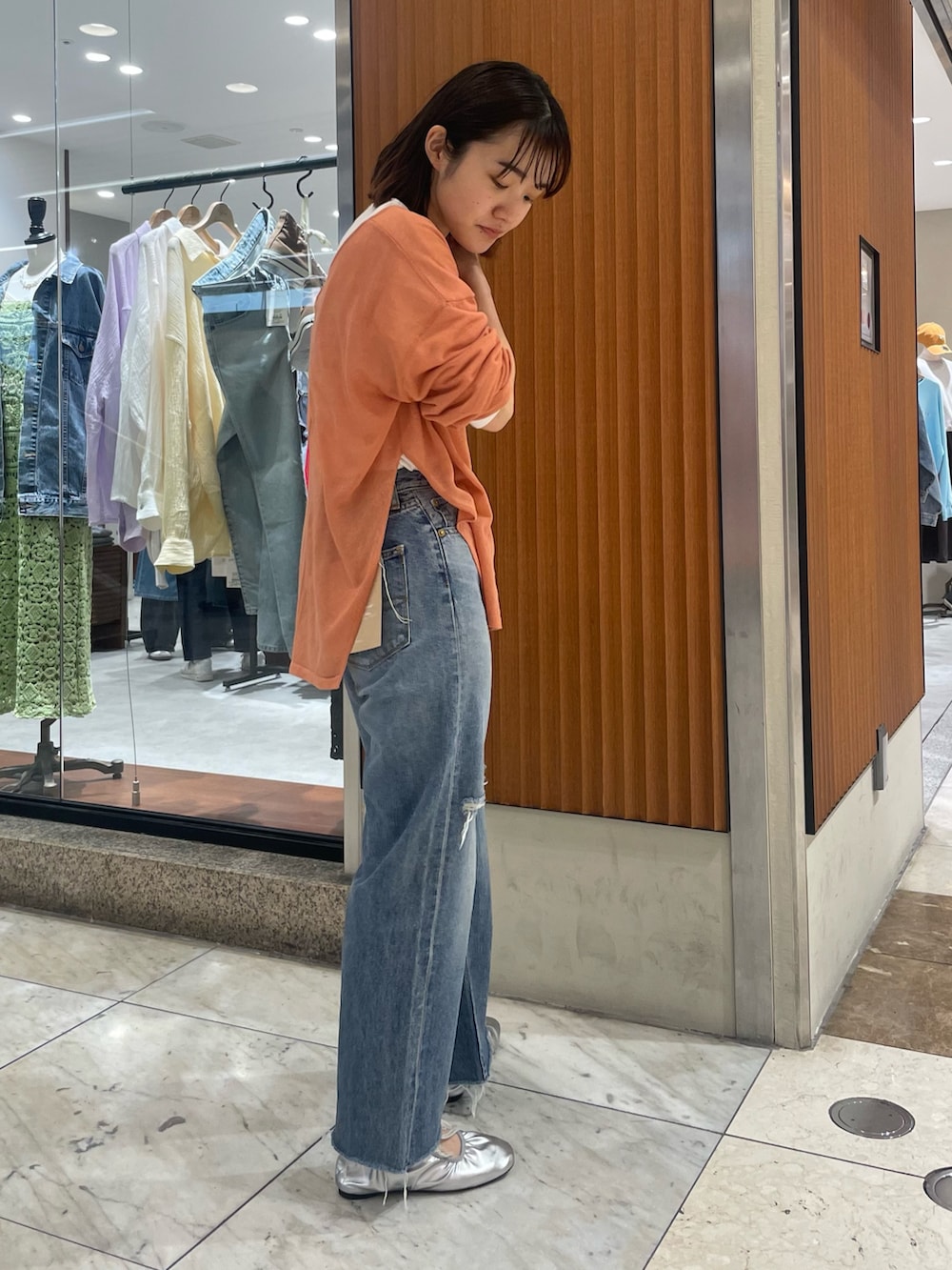 オレンジ系のニット/セーター、ブルー系のデニムパンツ、シルバー系のバレエシューズを着用したレディースの春コーディネートの2枚目の写真