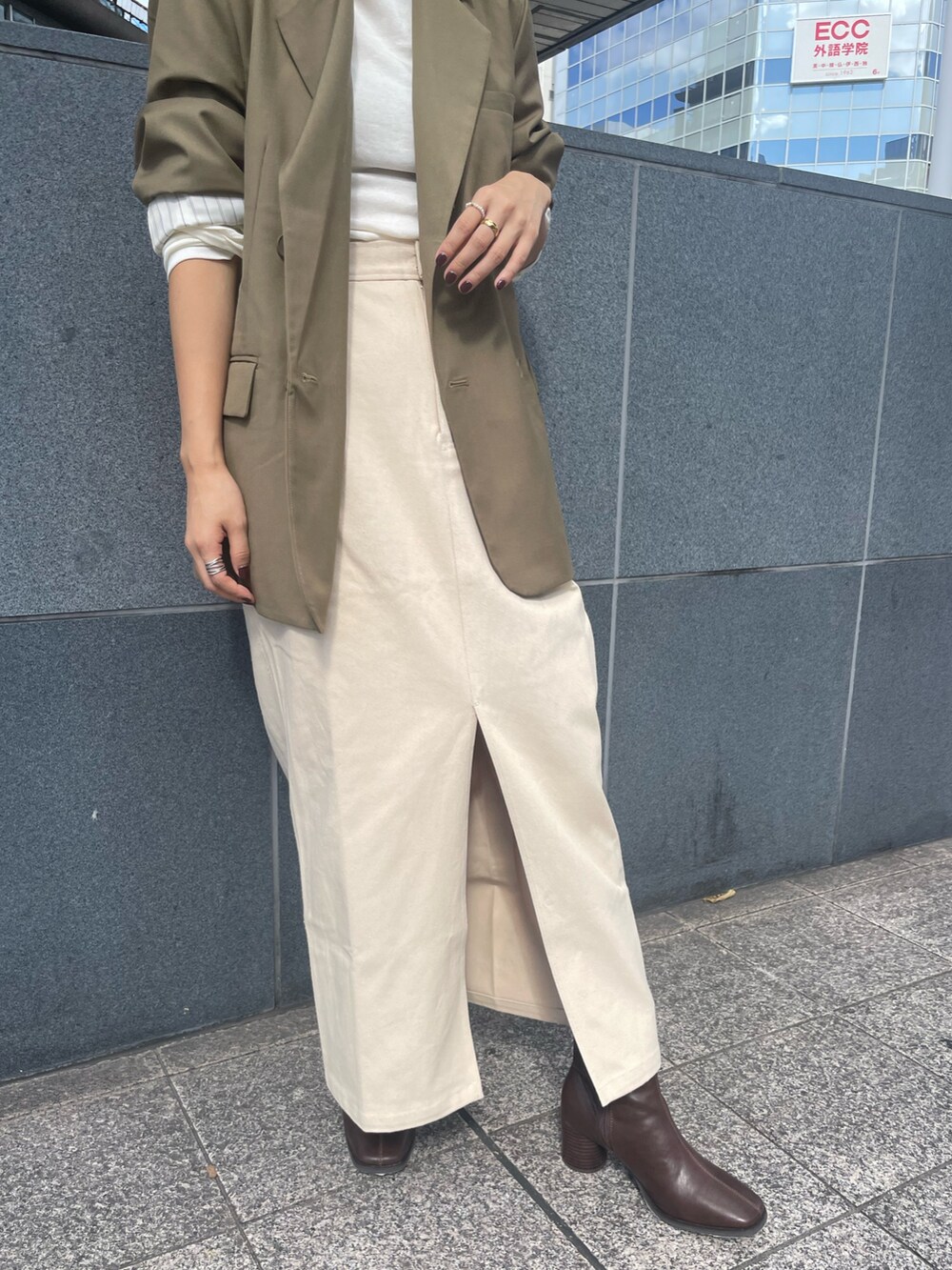ベージュ系のテーラードジャケット、ホワイト系のTシャツ/カットソー、ベージュ系のスカートを着用したレディースの秋コーディネートの5枚目の写真