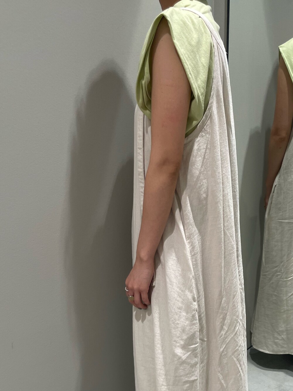 グリーン系のタンクトップ、ホワイト系のワンピース、ブルー系のデニムパンツを着用したレディースの夏コーディネートの4枚目の写真