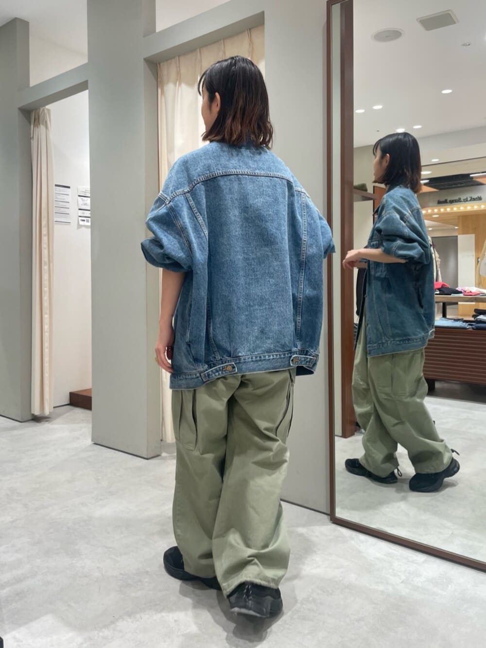 ブルー系のデニムジャケット、グリーン系のその他パンツ、ブラック系のスニーカーを着用したレディースの春コーディネートの3枚目の写真