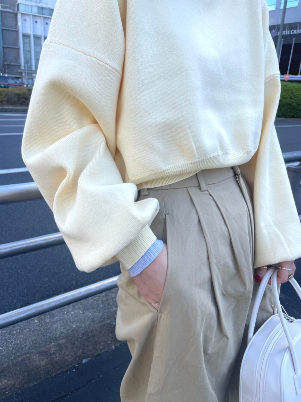 イエロー系のニット/セーター、ベージュ系のチノパンツ、ホワイト系のボストンバッグを着用したレディースの冬コーディネートの4枚目の写真