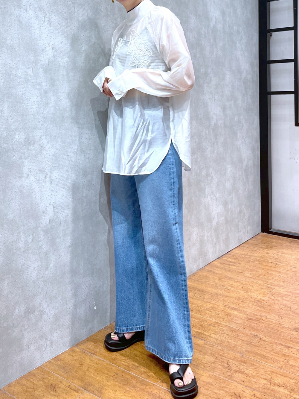 ホワイト系のシャツ/ブラウス、ブラック系のサンダル、ブルー系のデニムパンツを着用したレディースの夏コーディネートの3枚目の写真