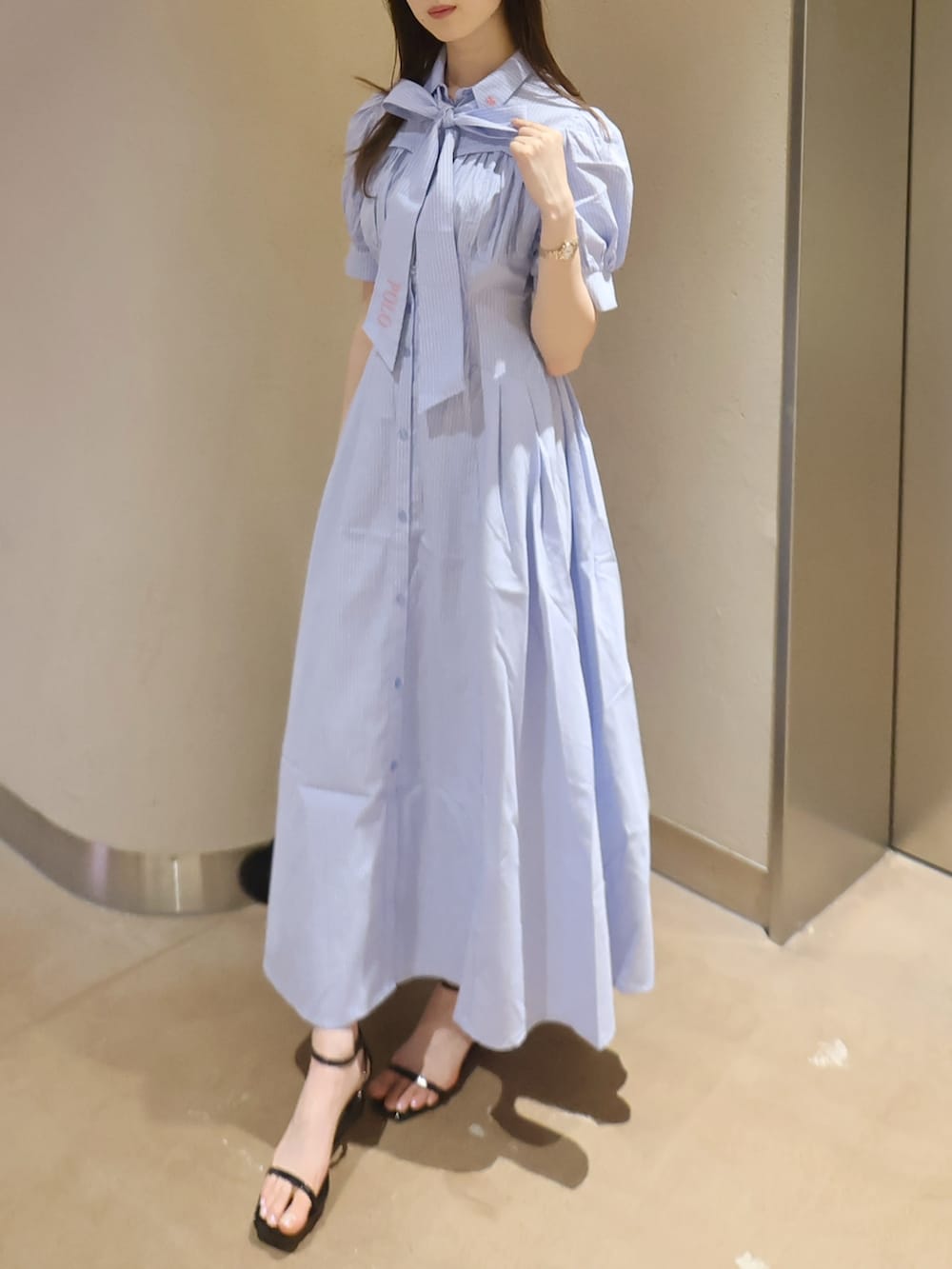 ブラック系のサンダル、ブラック系のハンドバッグ、ブルー系のワンピースを着用したレディースの夏コーディネートの4枚目の写真