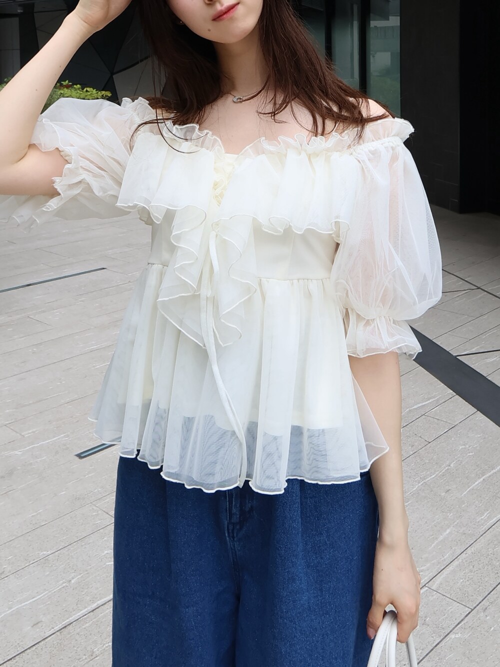 ホワイト系のボストンバッグ、ホワイト系のシャツ/ブラウス、ブルー系のデニムパンツを着用したレディースの夏コーディネートの4枚目の写真