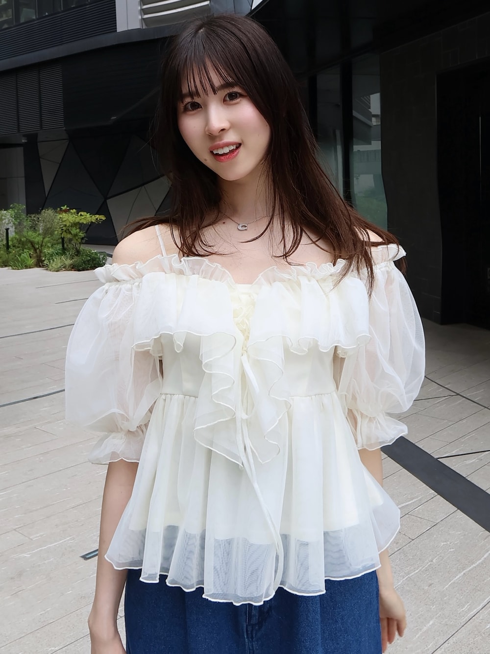 ホワイト系のボストンバッグ、ホワイト系のシャツ/ブラウス、ブルー系のデニムパンツを着用したレディースの夏コーディネートの5枚目の写真