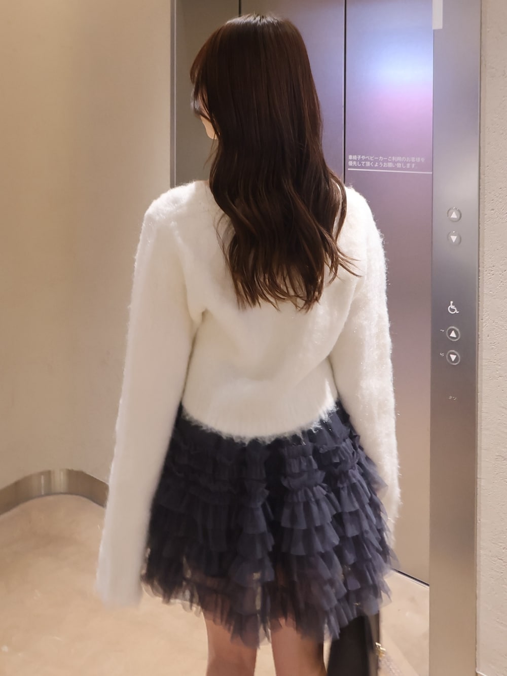 ホワイト系のカーディガン/ボレロ、グレー系のスカート、ブラウン系のショルダーバッグを着用したレディースの冬コーディネートの5枚目の写真