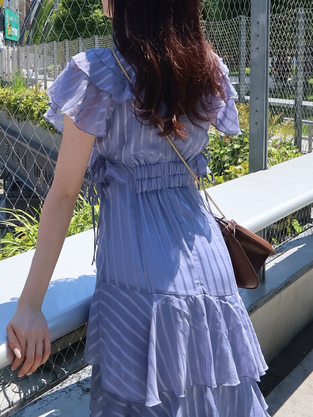 ブラウン系のサンダル、ブラウン系のハンドバッグ、ブルー系のワンピースを着用したレディースの夏コーディネートの5枚目の写真