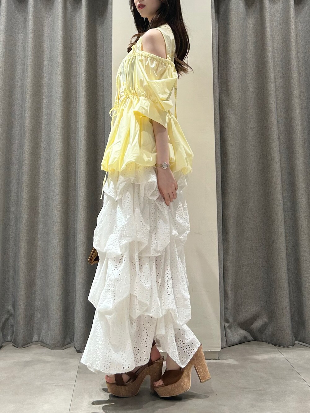 イエロー系のシャツ/ブラウス、ホワイト系のスカート、ブラウン系のサンダルを着用したレディースの夏コーディネートの2枚目の写真