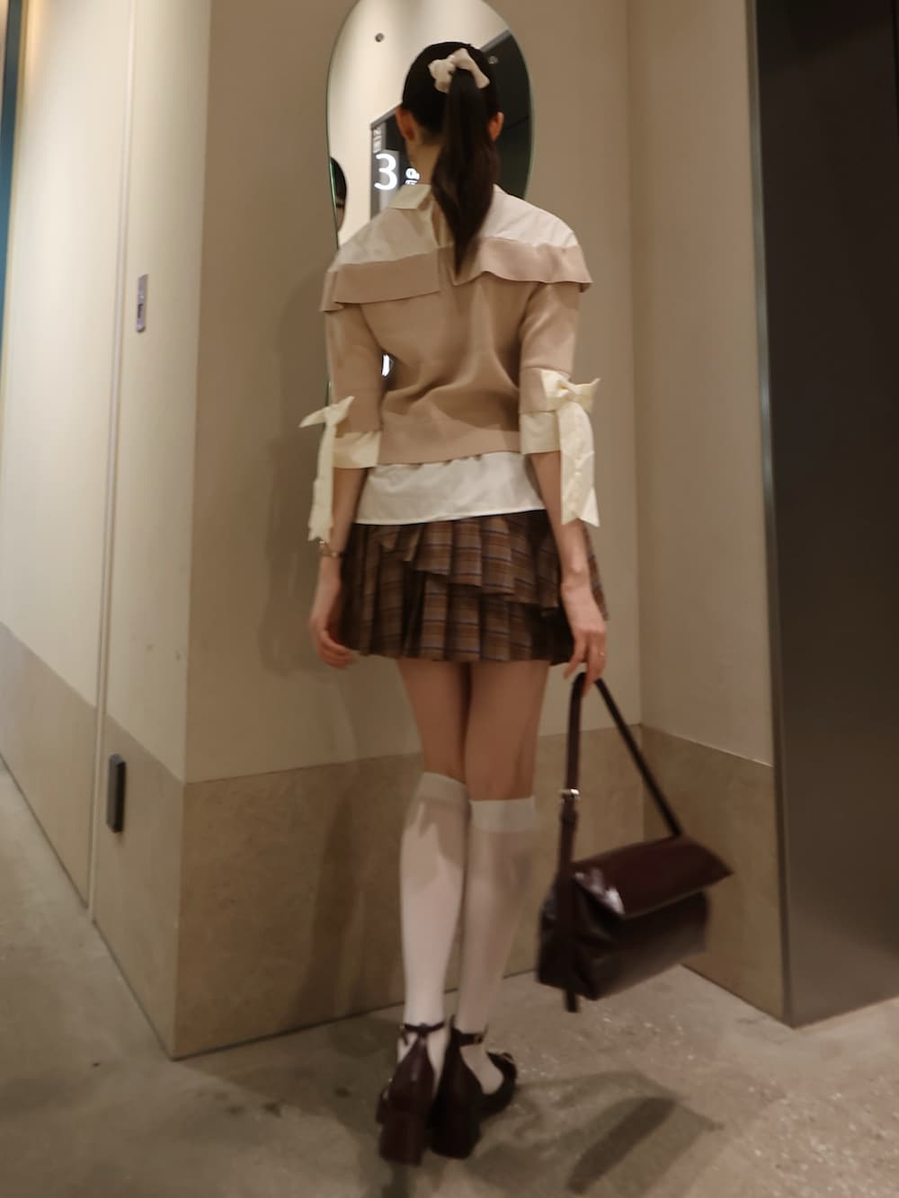 ベージュ系のニット/セーター、ブラウン系のスカート、レッド系のパンプスを着用したレディースの秋コーディネートの3枚目の写真