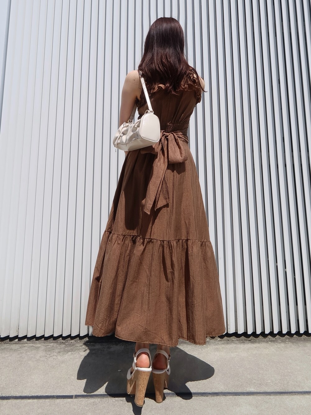 ブラウン系のワンピース、ホワイト系のサンダル、ホワイト系のハンドバッグを着用したレディースの夏コーディネートの3枚目の写真